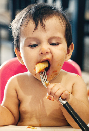 cute baby eating pasta with fork