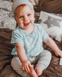 cute little happy baby girl plays sitting on a bed
